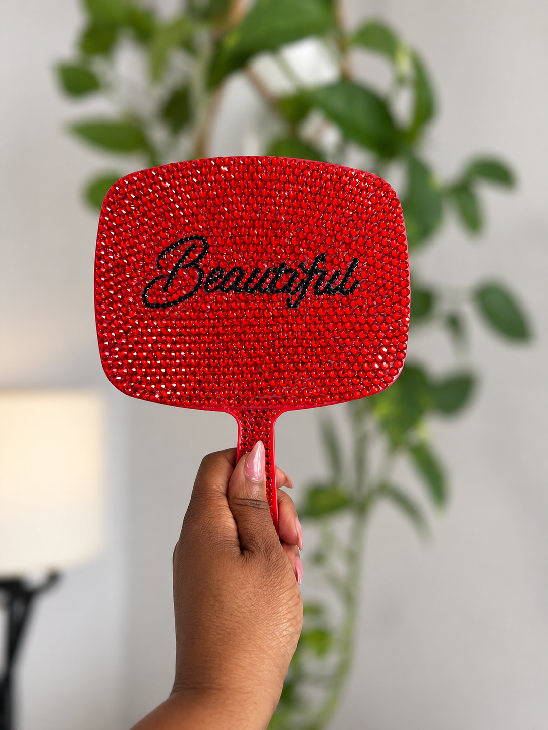 Red crystal vanity mirror held upright by hand