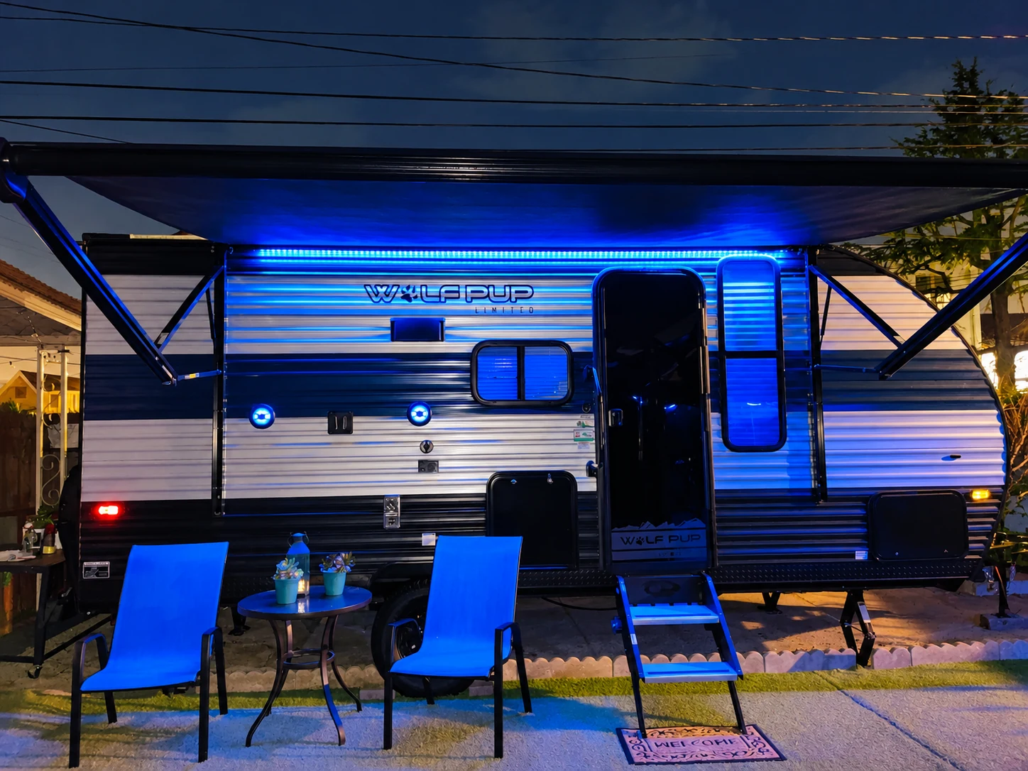 The So Fly glamper at night, illuminated with blue lights